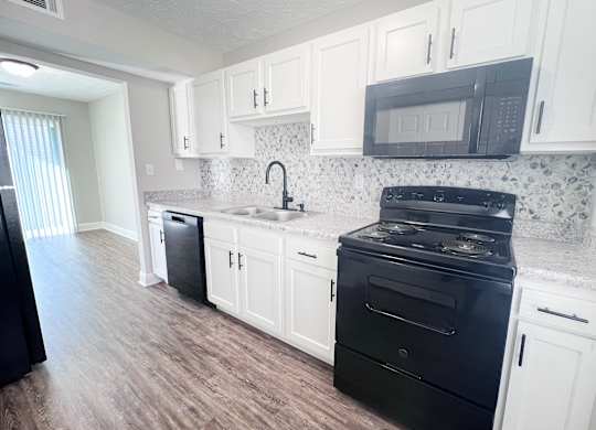 A kitchen with black appliances and white cabinets.