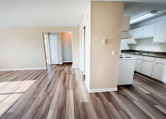 A kitchen with white cabinets and a wooden floor.
