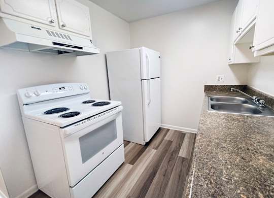 A kitchen with a white stove, white cabinets, and a white refrigerator.