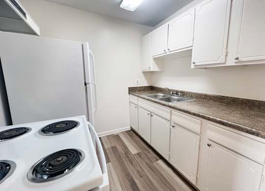 A kitchen with a white stove and cabinets.
