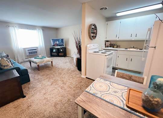 A living room with a couch, a coffee table, and a kitchen area in the background.