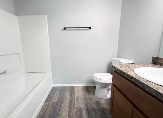 A white toilet sits in a bathroom next to a sink.
