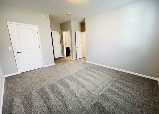 an empty living room with carpet and white doors  at Brookfield Village Apartments, Grove City, OH, 43123