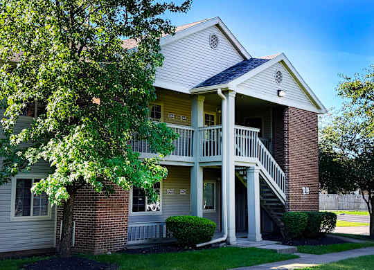 A two-story house with a balcony and a tree in front.