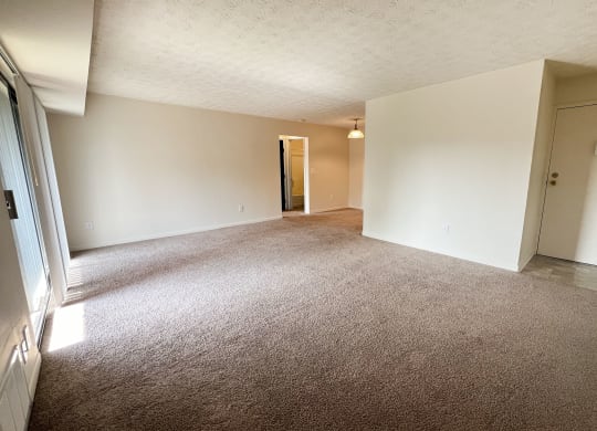 an empty living room with carpet and white walls at Four Worlds Apartments, Cincinnati, Ohio