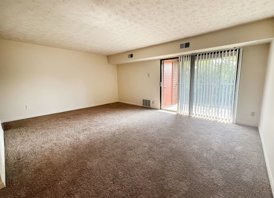 an empty living room with a sliding glass door to a balcony at Four Worlds Apartments, Cincinnati, OH