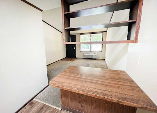 A room with a long wooden table and a window with a view of trees.