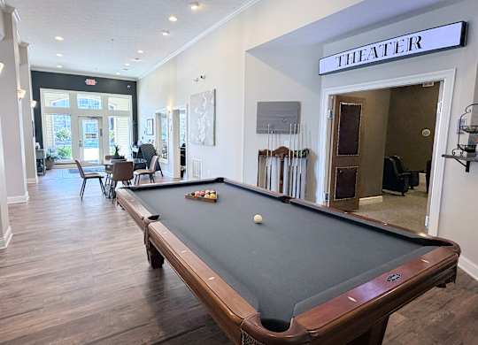 A pool table in a room with a sign that says "THEATER".