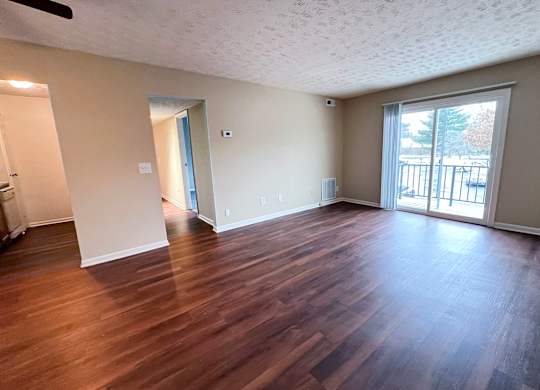 A room with wooden flooring and a sliding glass door.