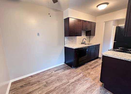 A kitchen with a black refrigerator and brown cabinets.