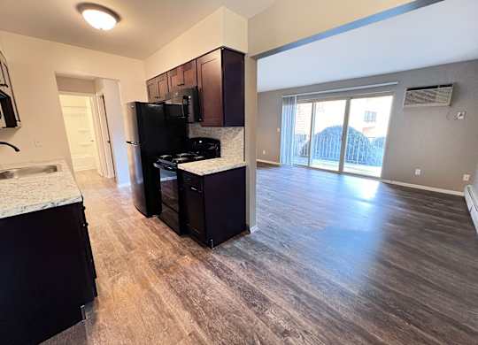 A kitchen with dark wood cabinets and a black fridge.