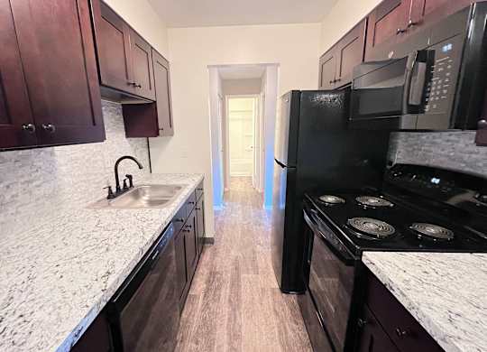 A kitchen with dark wood cabinets and a black stove top oven.