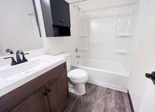 A white toilet sits in a bathroom next to a sink and a bathtub.