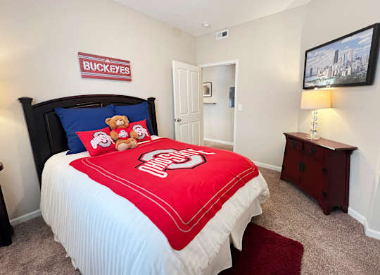 a bedroom with a bed with a red comforter at The Residences at Liberty Crossing, Columbus, 43235