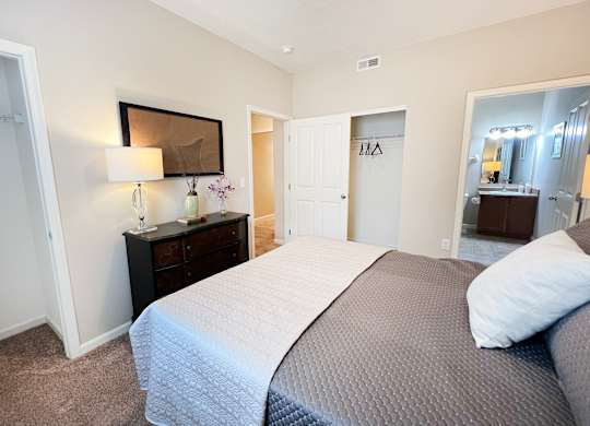 a bedroom with a large bed and a bathroom with a mirror at The Residences at Liberty Crossing, Columbus, OH, 43235