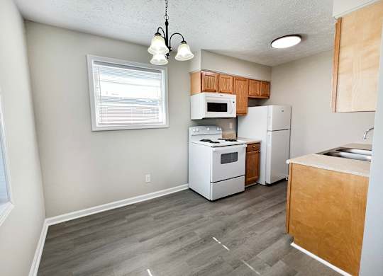 A kitchen with white appliances and wooden cabinets.