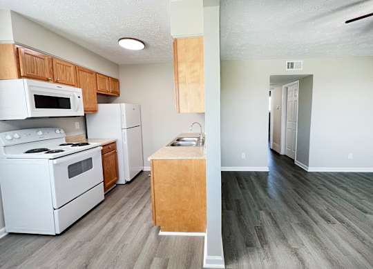 A kitchen with white appliances and wooden cabinets.