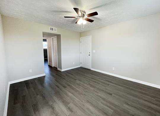 A room with a ceiling fan and wooden flooring.