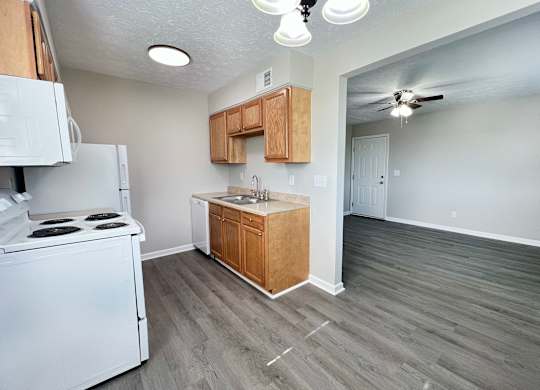 A kitchen with a white stove top oven and a white refrigerator.