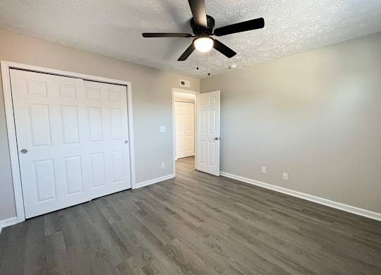 A room with a ceiling fan and two doors.