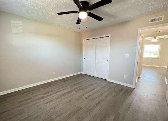 A room with a ceiling fan and a door.