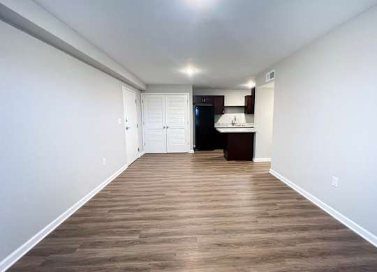 A long, narrow room with wood flooring and white walls.