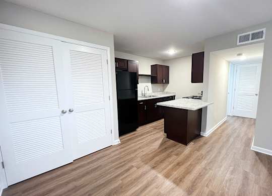A kitchen with white cabinets and a black fridge.