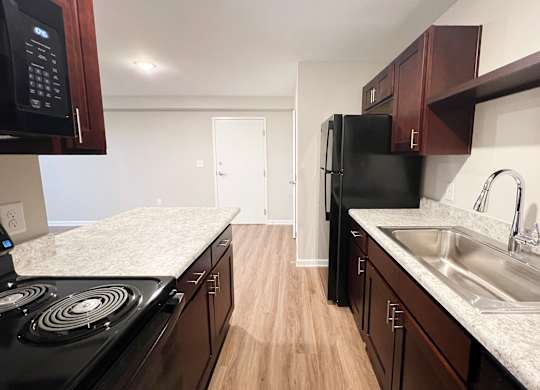 A kitchen with black appliances and wooden cabinets.