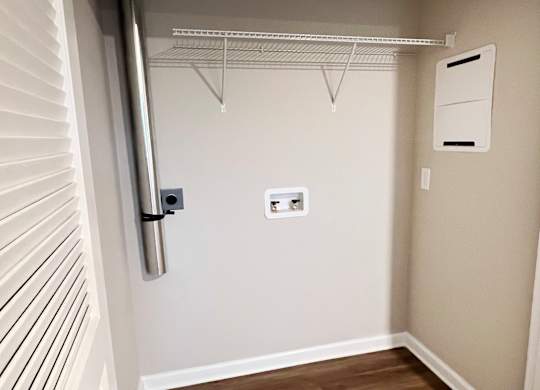 A white door with a silver handle and a white wall with a white shelf on it.