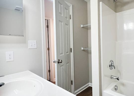 A white bathroom with a white tub and a white sink.