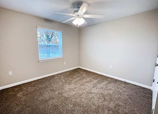 A room with a ceiling fan and carpeted floor.