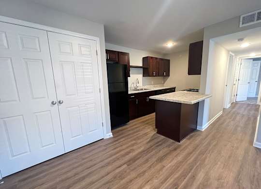 A kitchen with white cabinets and a wooden floor.