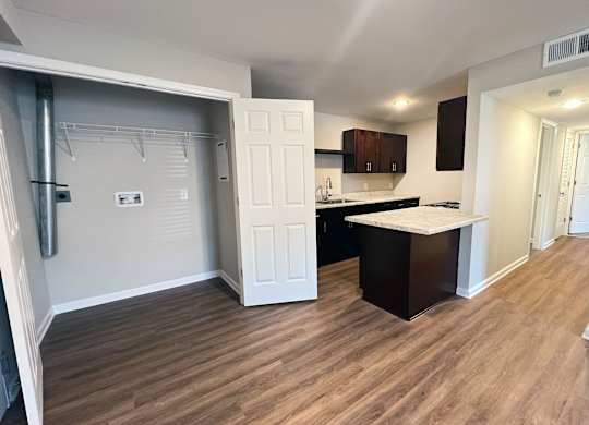A kitchen with a white door and a wooden floor.