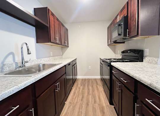 A kitchen with dark wood cabinets and a granite countertop.