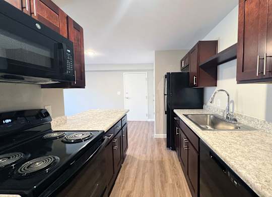 A kitchen with black appliances and wooden cabinets.