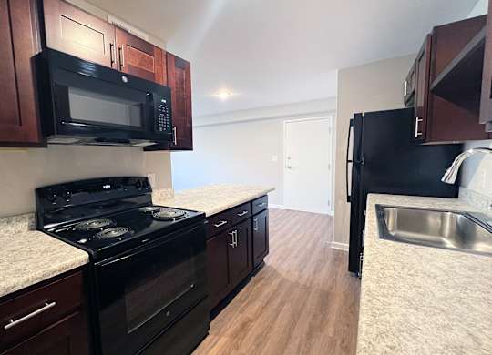 A kitchen with black appliances and wooden cabinets.