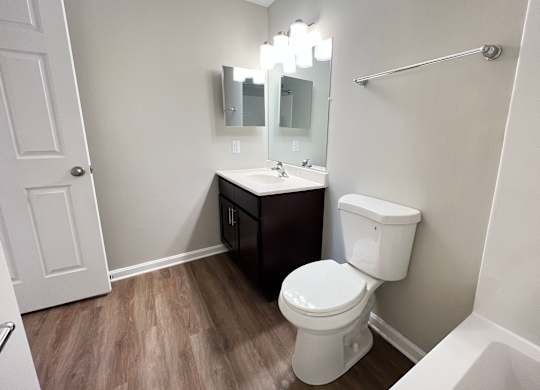 A white toilet sits in a bathroom with a sink and mirror.