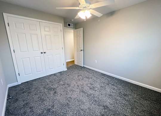 A room with a ceiling fan and carpeted floor.