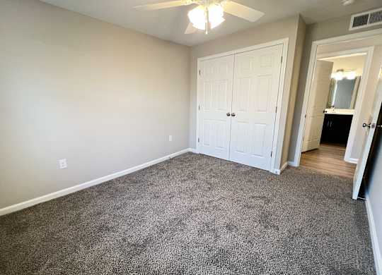 A room with a carpeted floor and a ceiling fan.