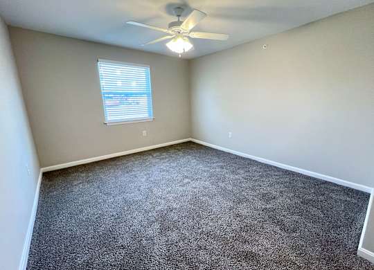 A room with a ceiling fan and carpeted floor.