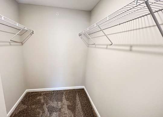 A walk-in closet with a carpeted floor and metal shelving.