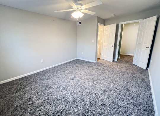 A room with a ceiling fan and carpeted floor.