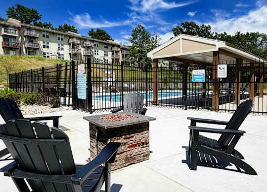 A black chair is in front of a fire pit and a gazebo.