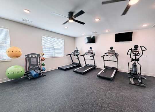 A room with a treadmill, exercise bike, and a ball.