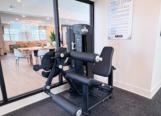 A gym room with a rowing machine and a sign on the wall.