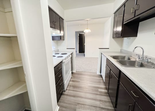an empty kitchen with black cabinets and a white stove and sink at Four Worlds Apartments, Ohio, 45231
