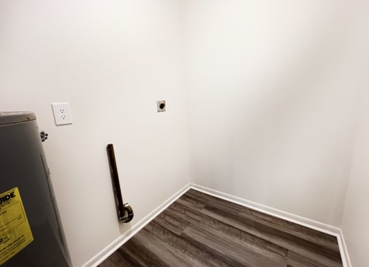 an empty room with a white wall and wooden floors at Four Worlds Apartments, Cincinnati, OH