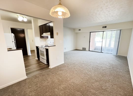 an empty living room and kitchen with a sliding glass door at Four Worlds Apartments, Ohio