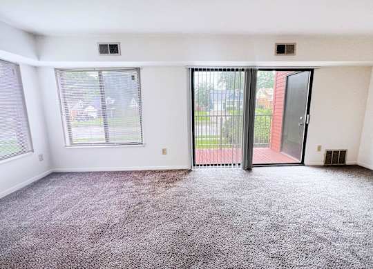 A room with a carpeted floor and a sliding glass door.