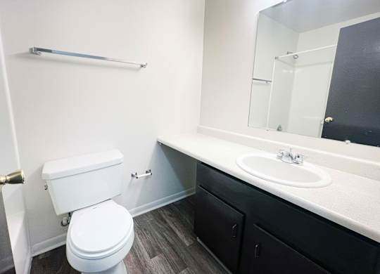A white toilet sits in a bathroom next to a sink.